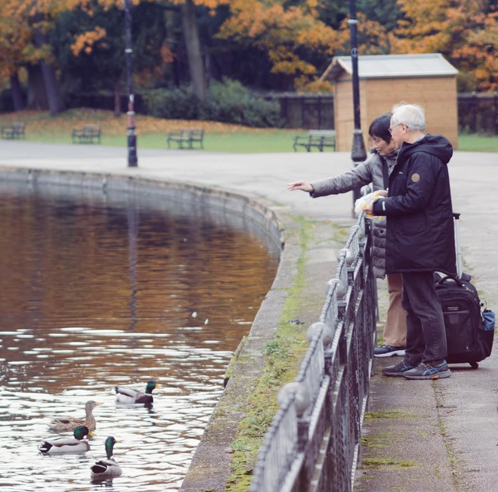 An image of two people feeding the ducks at Cannon Hill Park.
