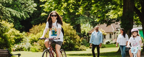 Woman cycling her bike through a park