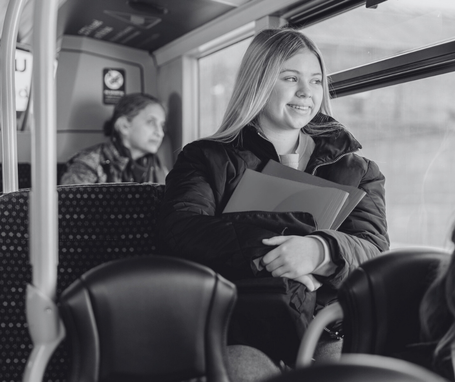A girl sat on the bus with her school books.